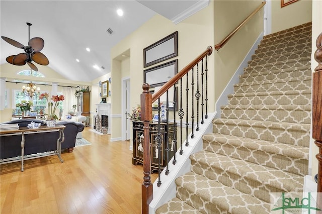 stairs with ceiling fan with notable chandelier, lofted ceiling, and hardwood / wood-style floors