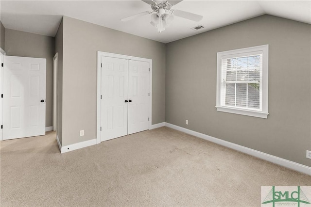 unfurnished bedroom featuring ceiling fan, a closet, vaulted ceiling, and light carpet