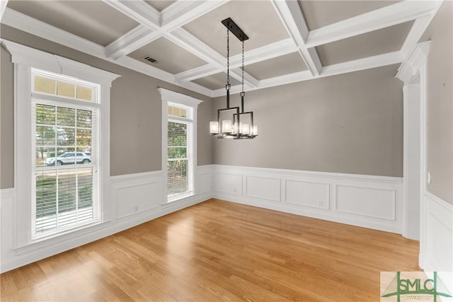 unfurnished dining area with beamed ceiling, coffered ceiling, light hardwood / wood-style flooring, and a notable chandelier