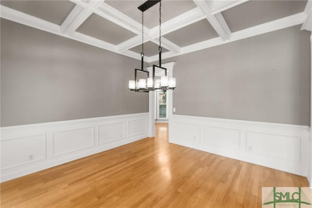 unfurnished dining area with beamed ceiling, coffered ceiling, hardwood / wood-style floors, and an inviting chandelier