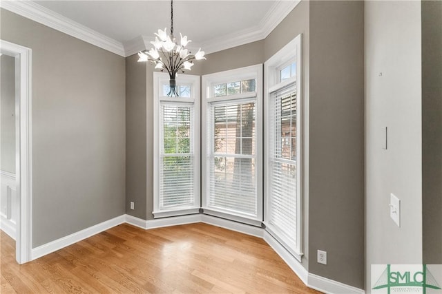 unfurnished dining area with an inviting chandelier, crown molding, and light hardwood / wood-style floors