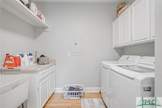 washroom featuring sink, electric panel, cabinets, independent washer and dryer, and light wood-type flooring