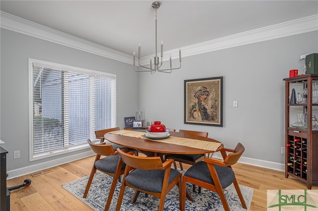 dining area featuring an inviting chandelier, ornamental molding, and light hardwood / wood-style floors