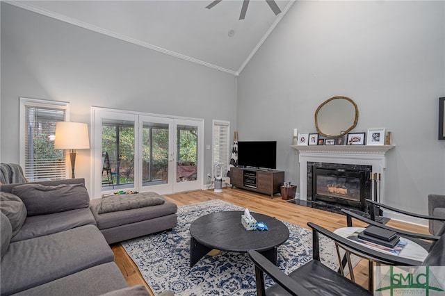 living room with crown molding, hardwood / wood-style flooring, high vaulted ceiling, a high end fireplace, and french doors