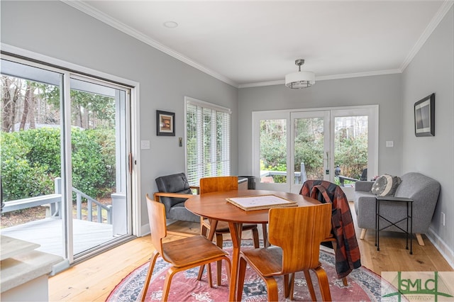 dining space with ornamental molding, light wood-type flooring, and french doors