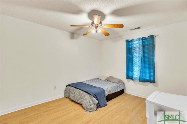 bedroom with hardwood / wood-style flooring, a textured ceiling, and ceiling fan