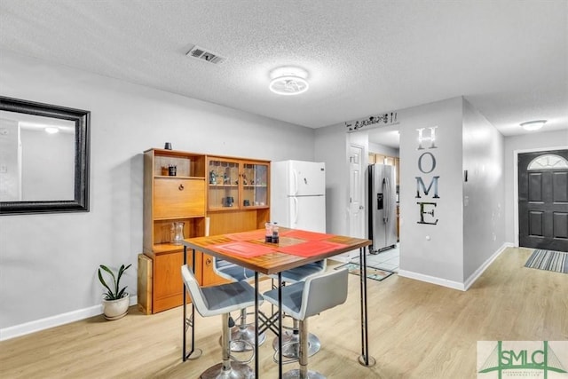 dining area featuring a textured ceiling and light hardwood / wood-style flooring