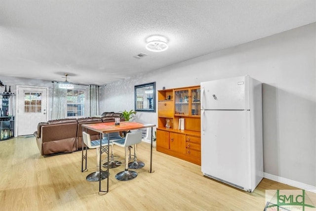 dining space featuring light hardwood / wood-style floors and a textured ceiling