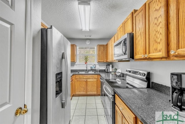 kitchen with sink, light tile patterned floors, a textured ceiling, and appliances with stainless steel finishes