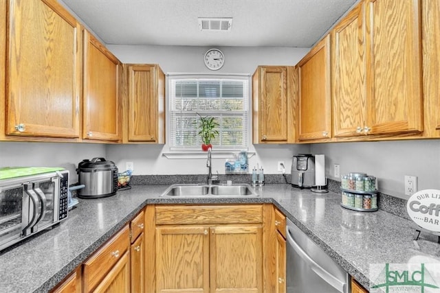 kitchen featuring dishwasher, sink, and a textured ceiling