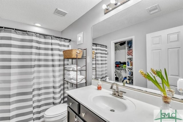 bathroom featuring vanity, a textured ceiling, and toilet