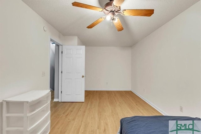 unfurnished bedroom with ceiling fan, a textured ceiling, and light wood-type flooring