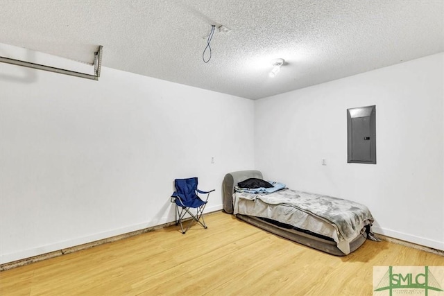 bedroom with hardwood / wood-style flooring, electric panel, and a textured ceiling