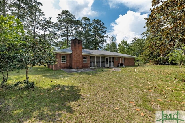 rear view of property featuring a sunroom, a patio area, and a lawn