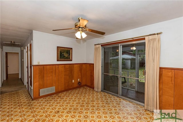 unfurnished room featuring ceiling fan and wooden walls