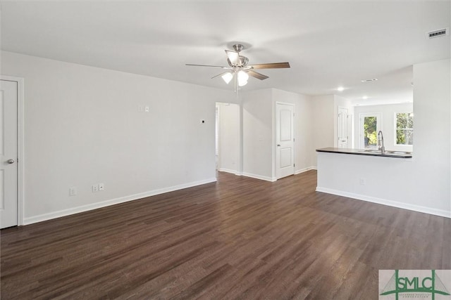 unfurnished living room with dark wood-type flooring, sink, and ceiling fan