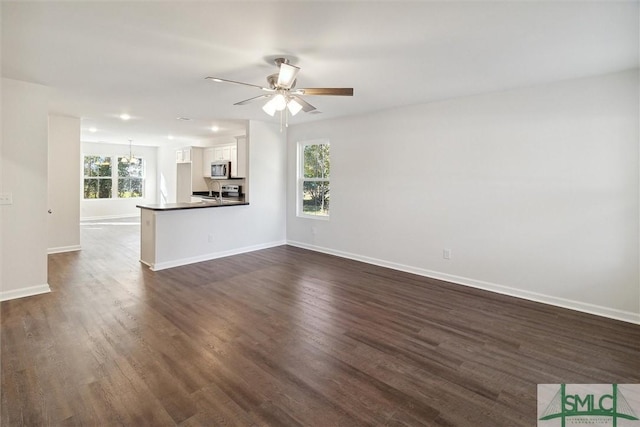 unfurnished living room featuring dark wood-type flooring and ceiling fan