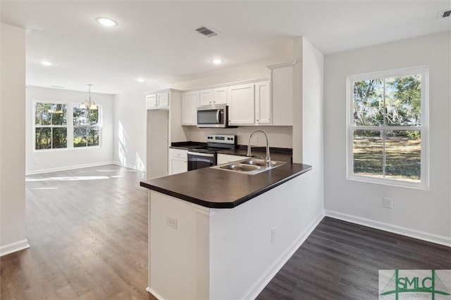 kitchen with appliances with stainless steel finishes, sink, white cabinets, hanging light fixtures, and kitchen peninsula