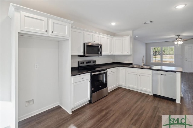 kitchen with appliances with stainless steel finishes, dark hardwood / wood-style floors, sink, white cabinets, and kitchen peninsula