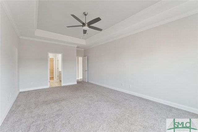 unfurnished room featuring a raised ceiling, ornamental molding, light carpet, and ceiling fan