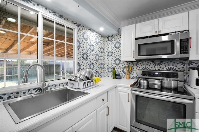 kitchen with ornamental molding, stainless steel appliances, sink, and white cabinets