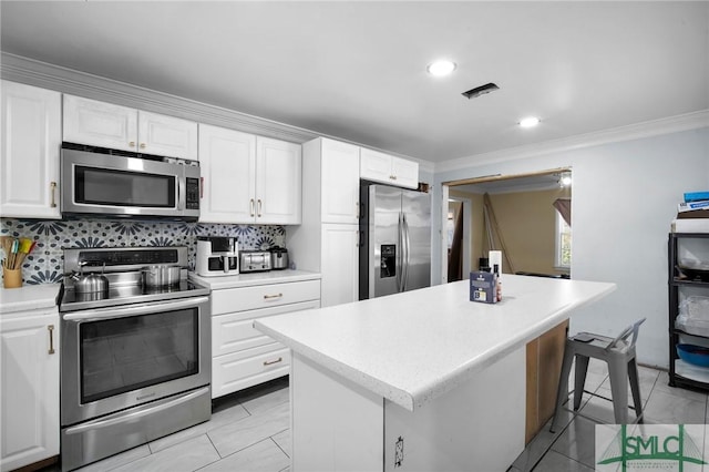 kitchen with a kitchen island, white cabinets, decorative backsplash, ornamental molding, and stainless steel appliances