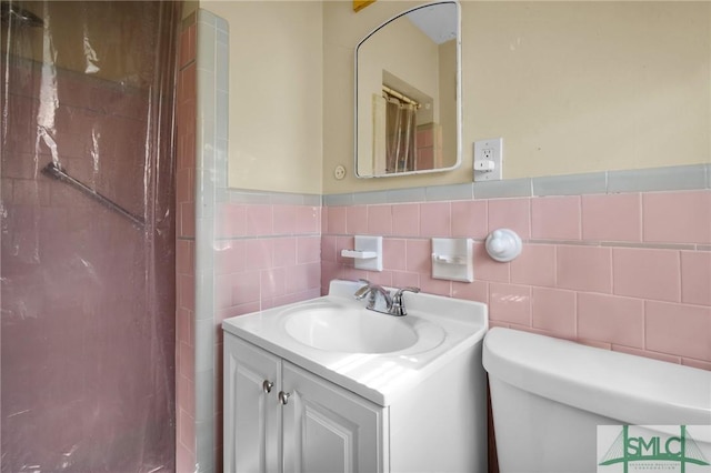 bathroom featuring vanity, toilet, and tile walls