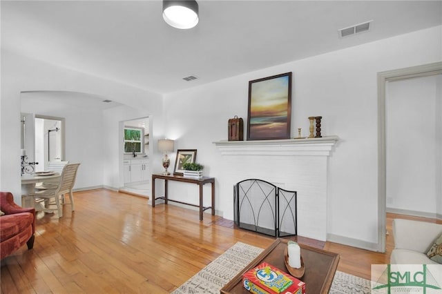 living room with a brick fireplace and light hardwood / wood-style flooring