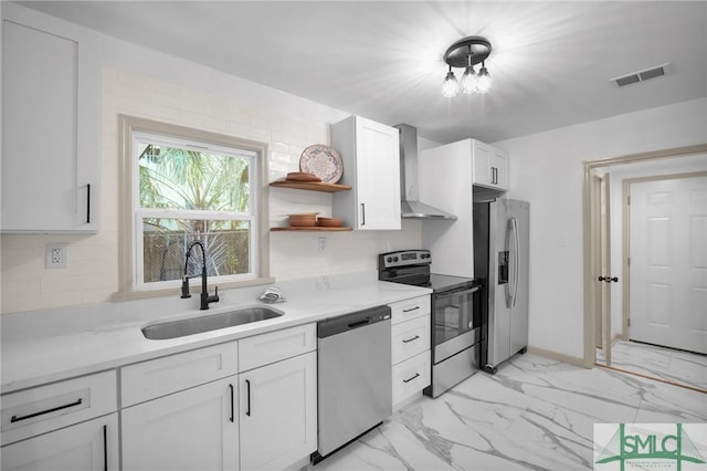 kitchen with sink, wall chimney range hood, white cabinets, and appliances with stainless steel finishes