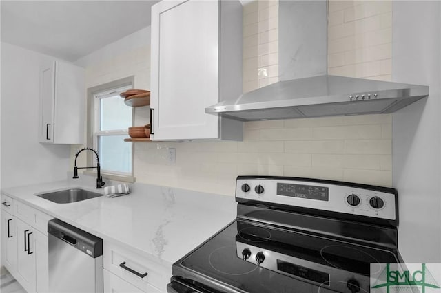 kitchen featuring appliances with stainless steel finishes, tasteful backsplash, white cabinetry, sink, and wall chimney range hood