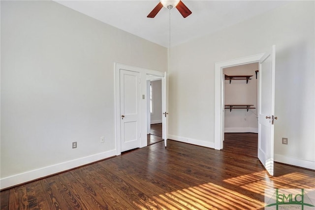 unfurnished bedroom featuring ceiling fan, dark hardwood / wood-style flooring, a closet, and a spacious closet