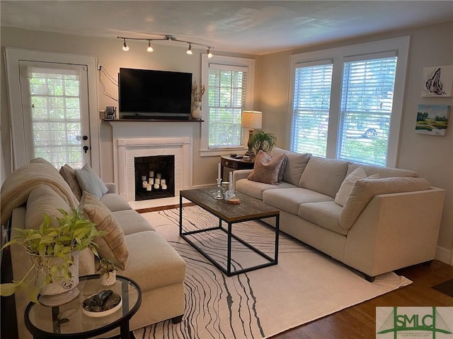 living room featuring rail lighting, a brick fireplace, and hardwood / wood-style floors