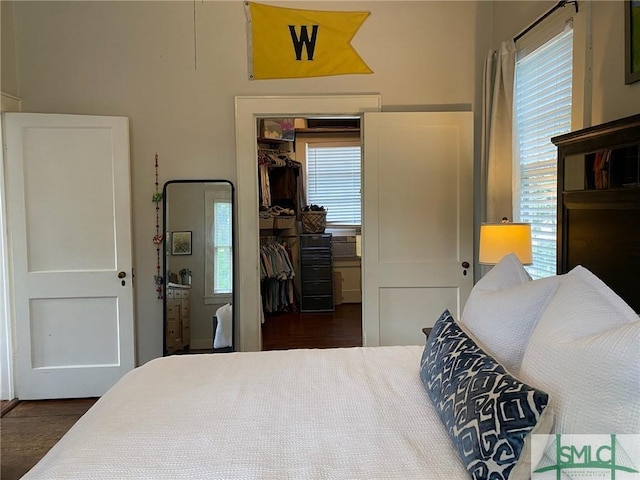 bedroom with a spacious closet, dark hardwood / wood-style floors, and a closet