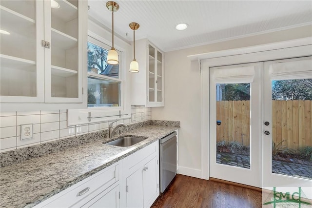 kitchen with pendant lighting, white cabinetry, dishwasher, sink, and light stone countertops