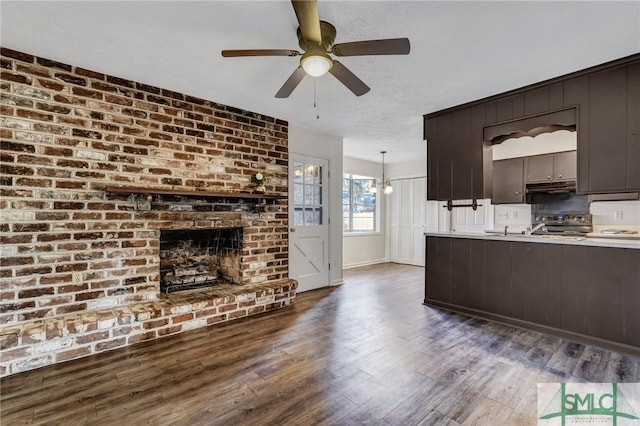 unfurnished living room featuring a brick fireplace, dark wood-type flooring, and ceiling fan