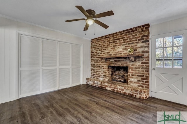 unfurnished living room with ceiling fan, a fireplace, ornamental molding, and dark hardwood / wood-style flooring