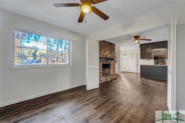 unfurnished living room with dark wood-type flooring, ceiling fan, and a fireplace