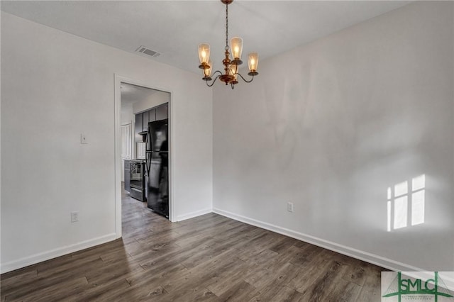 empty room featuring dark hardwood / wood-style floors and a chandelier