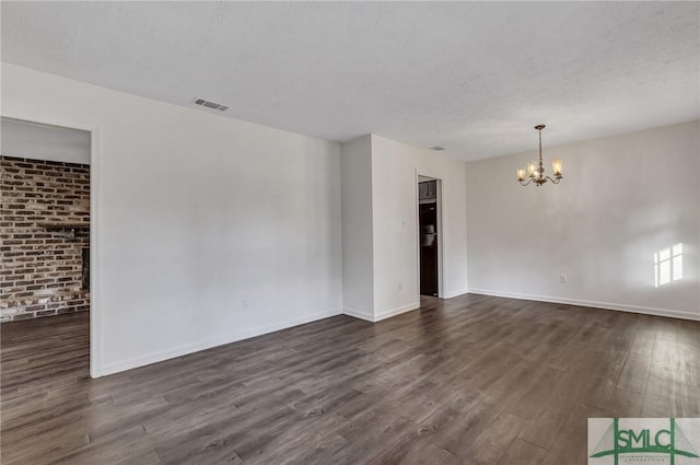 empty room featuring dark hardwood / wood-style floors, an inviting chandelier, and a textured ceiling