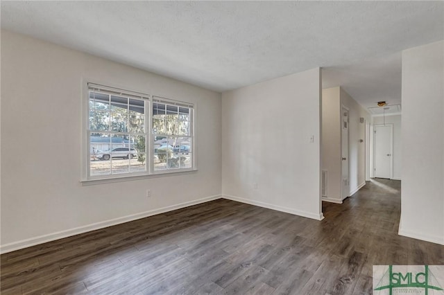 spare room featuring dark wood-type flooring and a textured ceiling