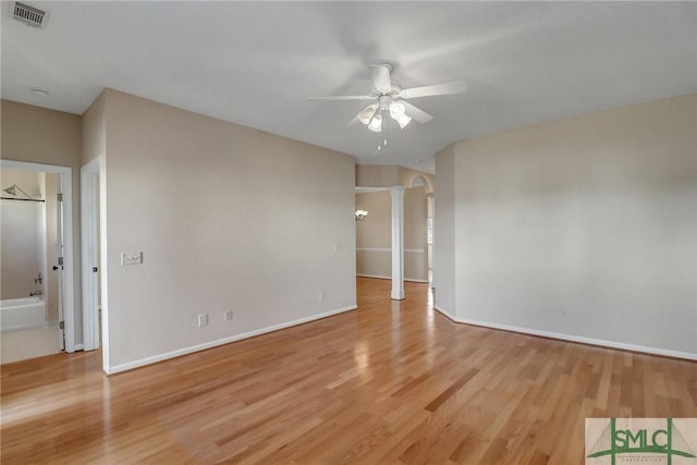 empty room with decorative columns, ceiling fan, and light wood-type flooring