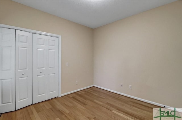 unfurnished bedroom with light wood-type flooring and a closet