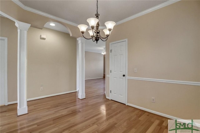 unfurnished dining area featuring hardwood / wood-style floors, crown molding, and ornate columns