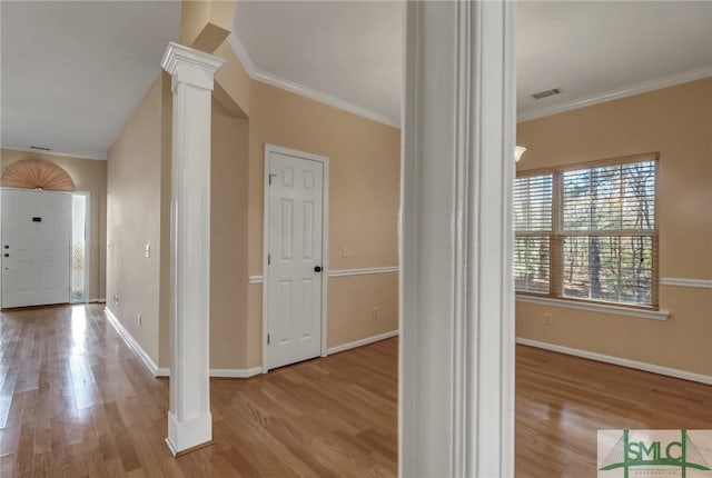 hall with crown molding, light wood-type flooring, and ornate columns