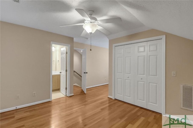 unfurnished bedroom featuring a closet, vaulted ceiling, light hardwood / wood-style flooring, and a textured ceiling