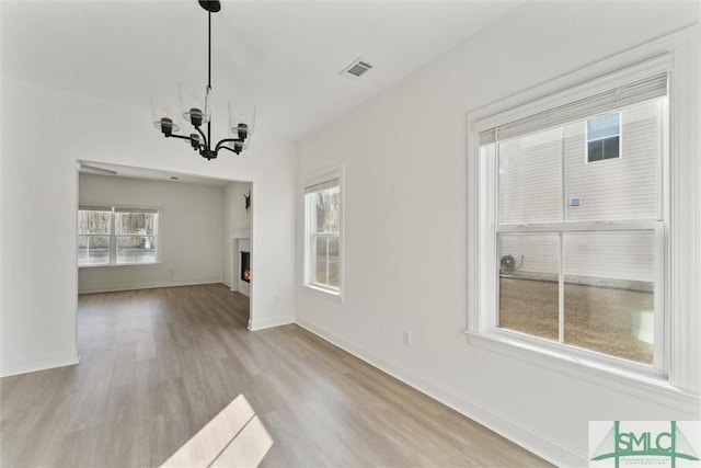 unfurnished dining area with a chandelier and light wood-type flooring