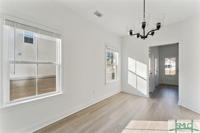 unfurnished dining area featuring a notable chandelier, light hardwood / wood-style flooring, and plenty of natural light