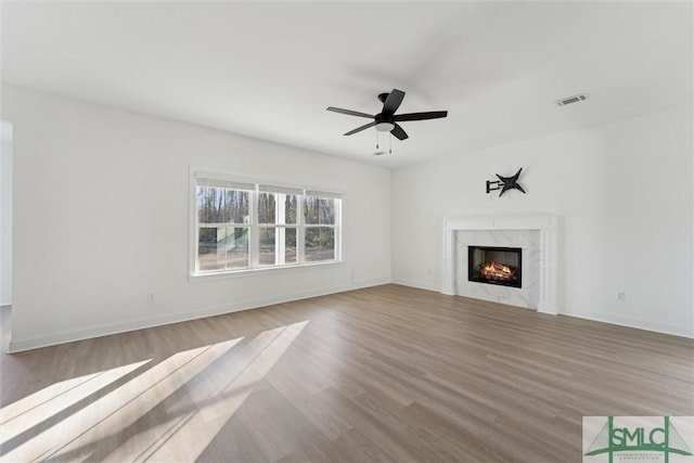 unfurnished living room with ceiling fan, a premium fireplace, and light hardwood / wood-style flooring