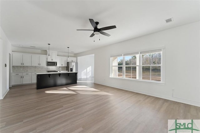 unfurnished living room with sink, light hardwood / wood-style floors, and ceiling fan