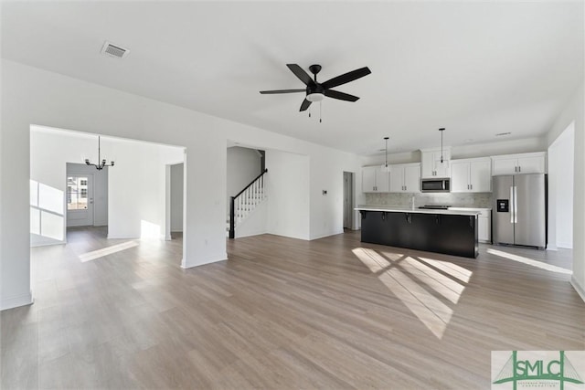 unfurnished living room with hardwood / wood-style flooring and ceiling fan with notable chandelier